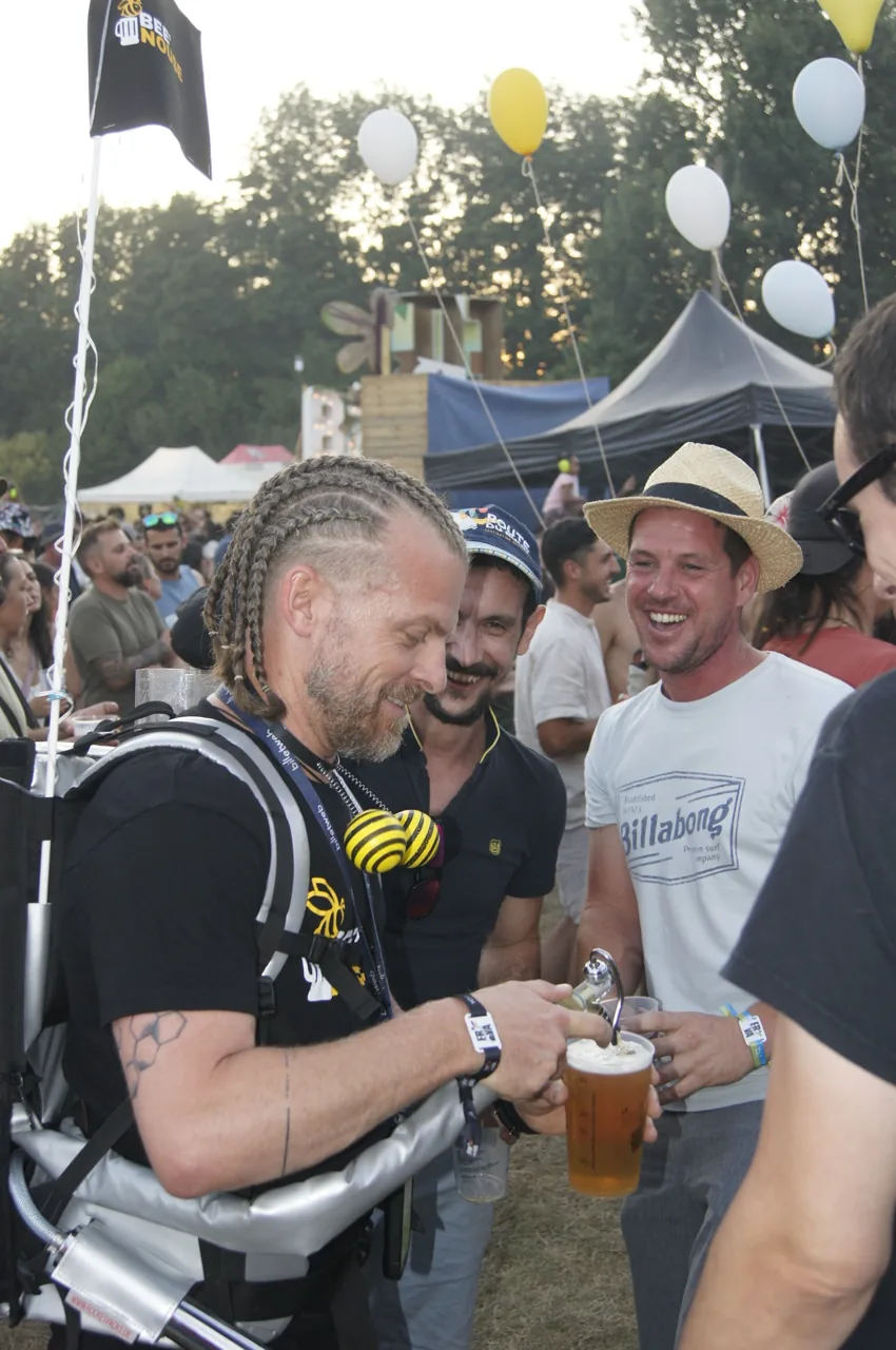 Un opérateur Bee’Nouse sert une boisson à un participant au milieu du public